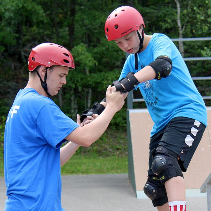 Staff helping camper learn to skateboard